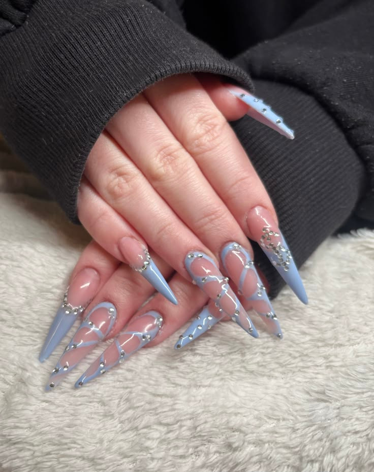 Long stiletto gel nails with pastel blue abstract swirl art and rhinestone accents