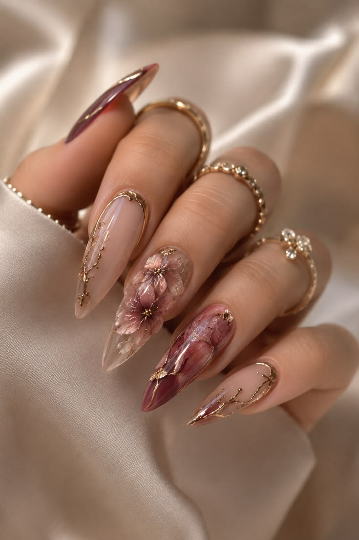 Elegant sheer nude stiletto nails with delicate floral art and metallic gold branches