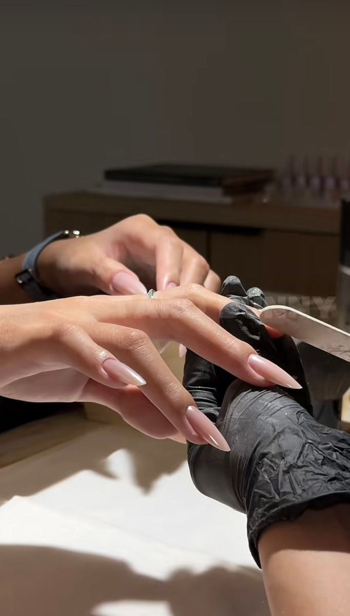 Professional technician filing long nude almond gel extensions