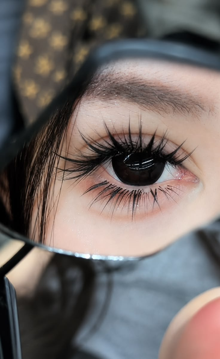 Manga style spiky lash extensions reflected in small hand mirror